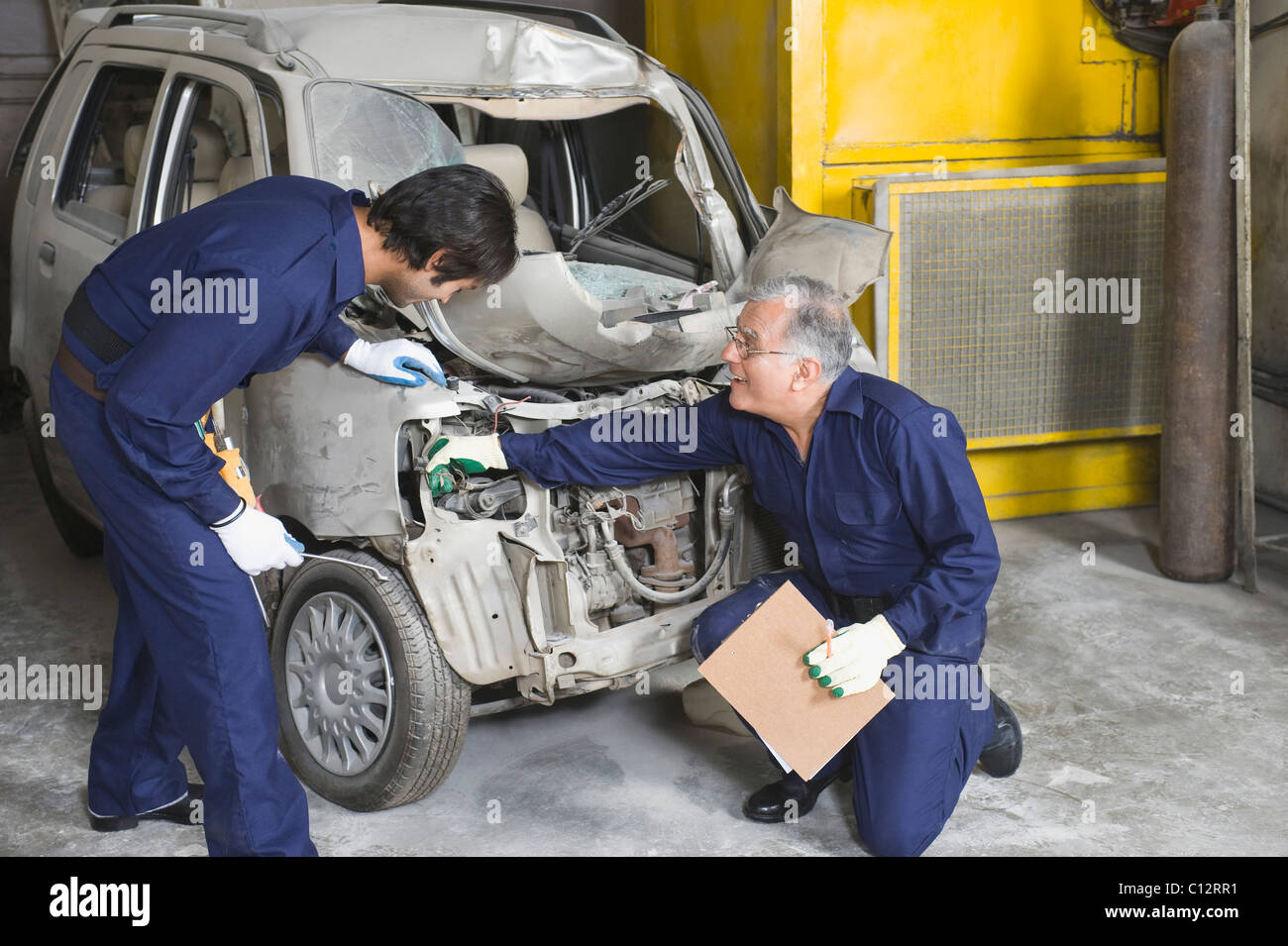 Auto mechanic with an apprentice repairing a car in a garage Stock Photo