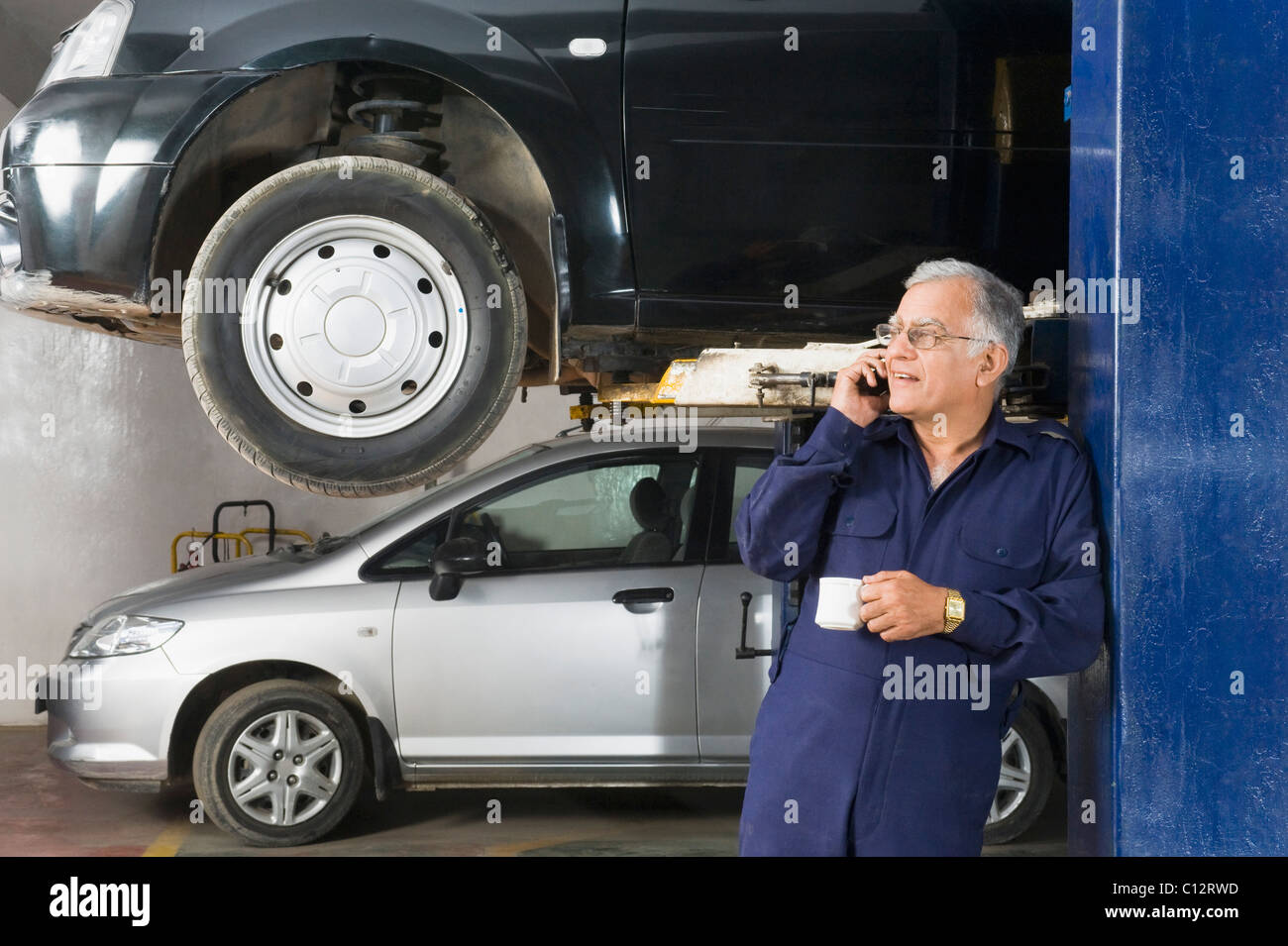 Auto mechanic talking on a mobile phone while drinking coffee in a garage  Stock Photo - Alamy
