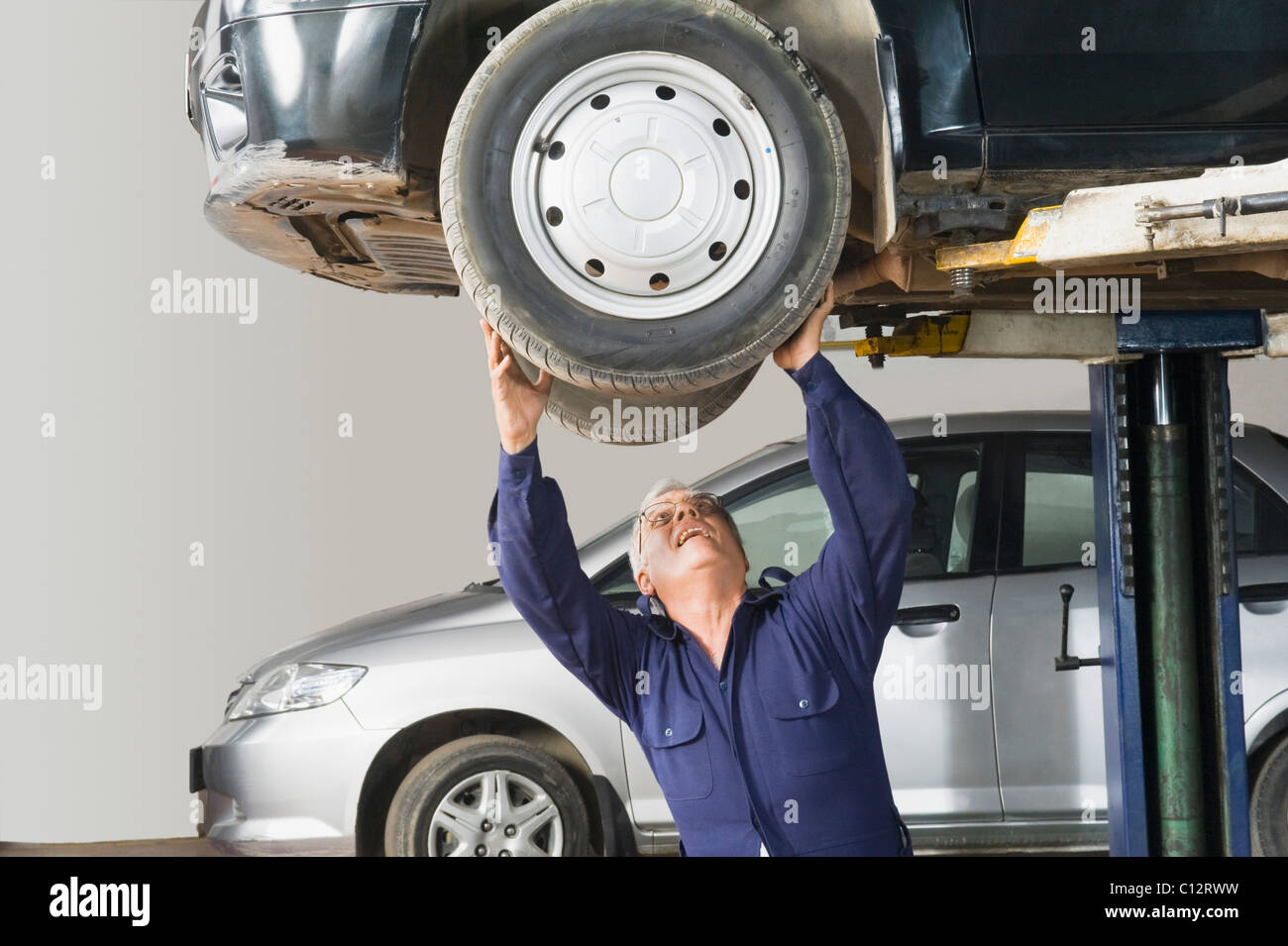 Auto mechanic working on a car wheel in a garage Stock Photo