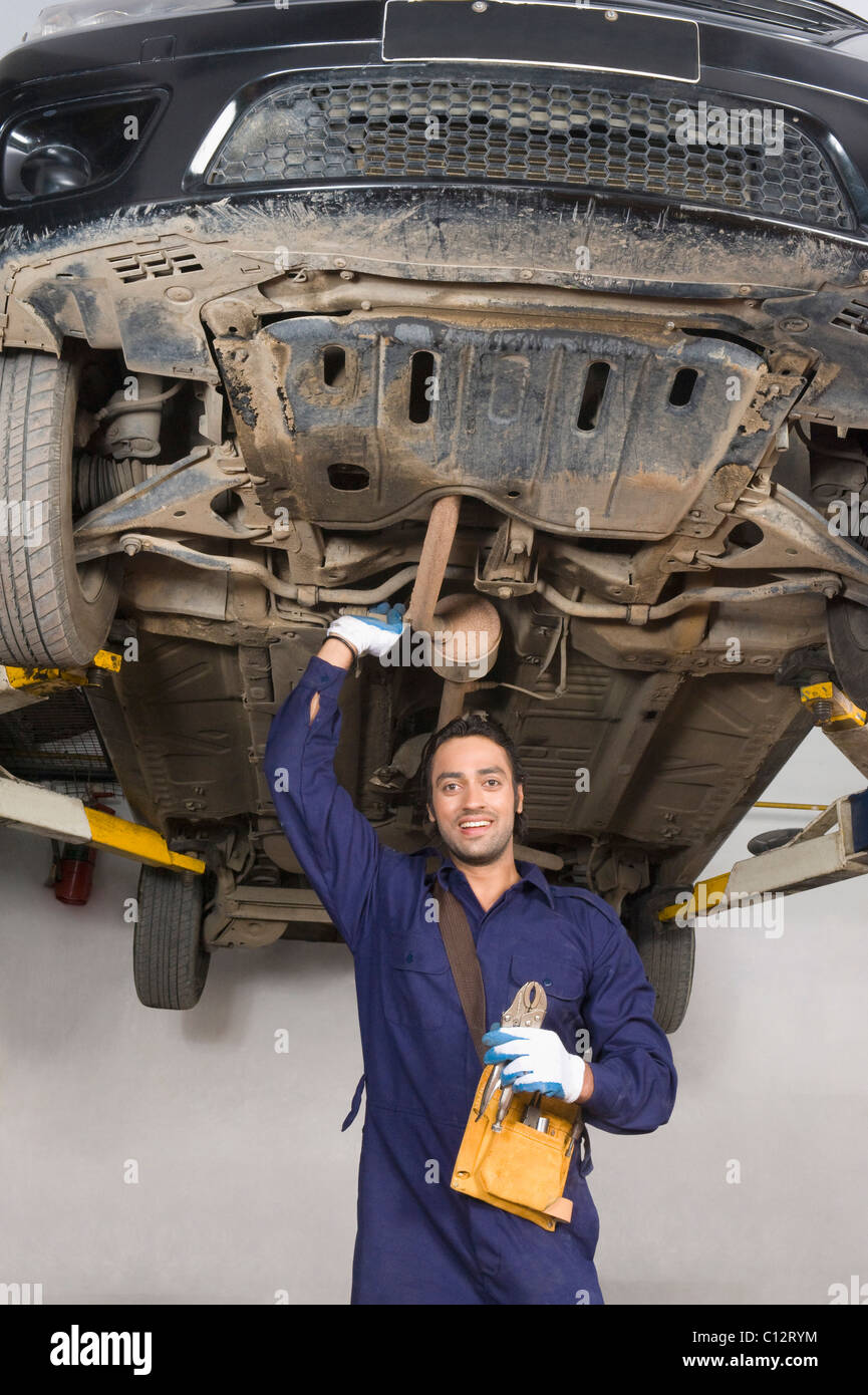 Auto mechanic working under a raised car in a garage Stock Photo
