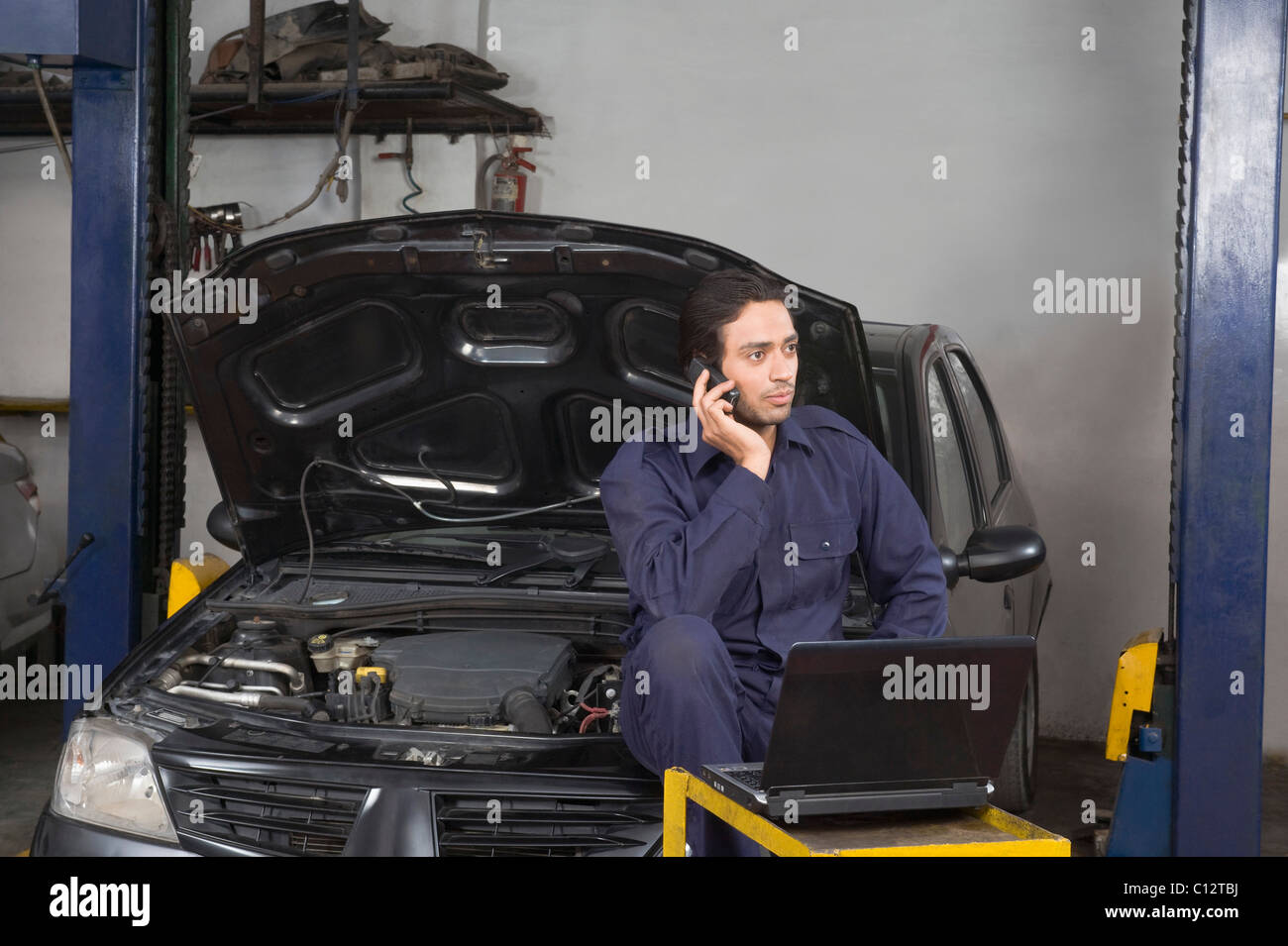 Auto mechanic talking on a mobile phone in a garage Stock Photo - Alamy