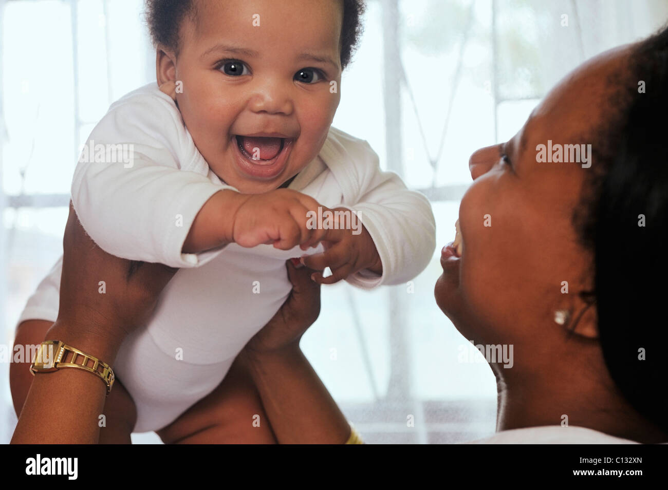 Mother holding laughing baby up. Cape Town, South Africa Stock Photo