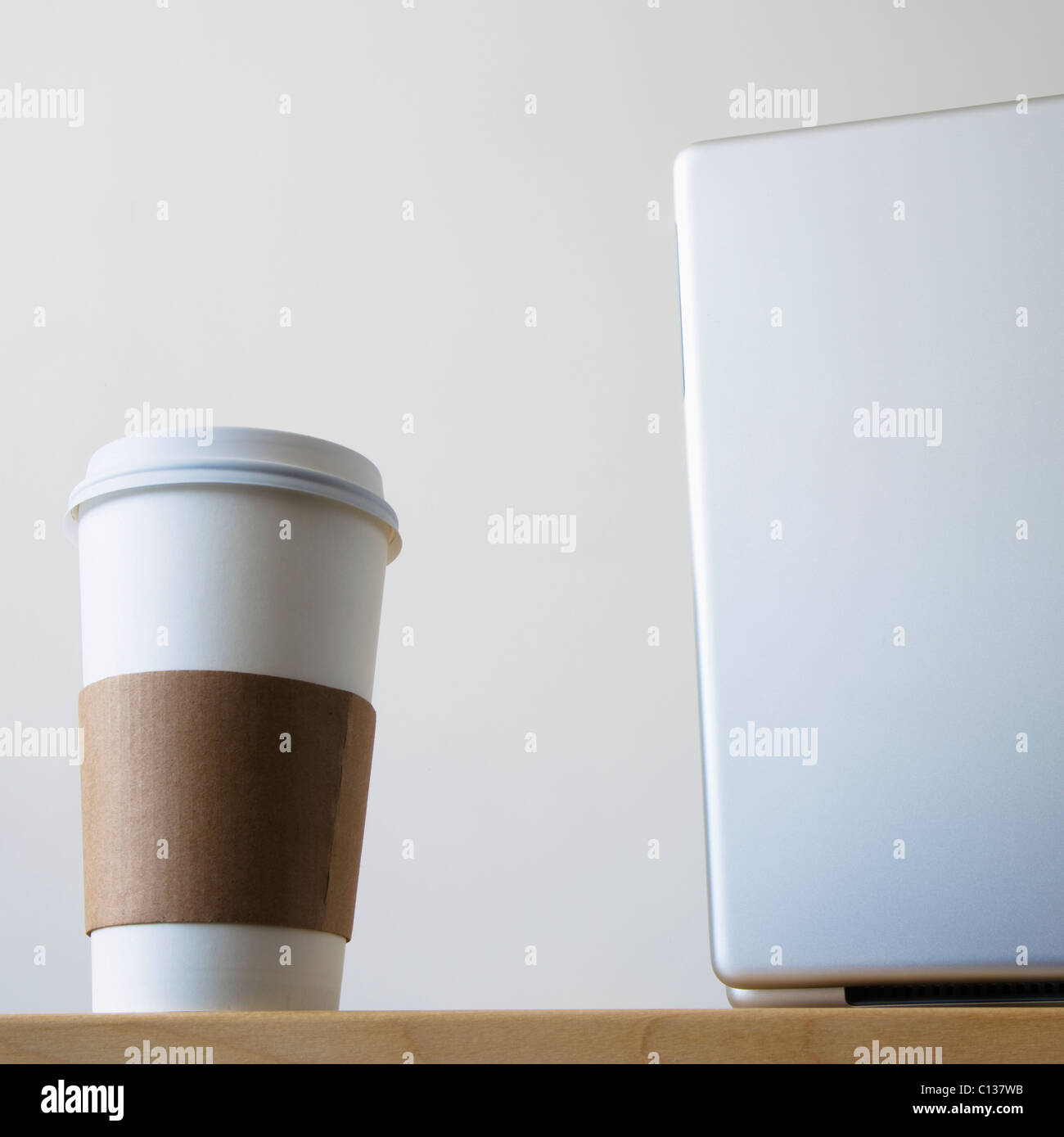 Coffee cup beside laptop in office Stock Photo