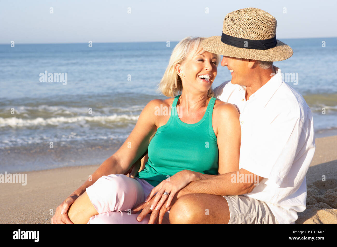 Senior couple sitting on beach relaxing Stock Photo - Alamy