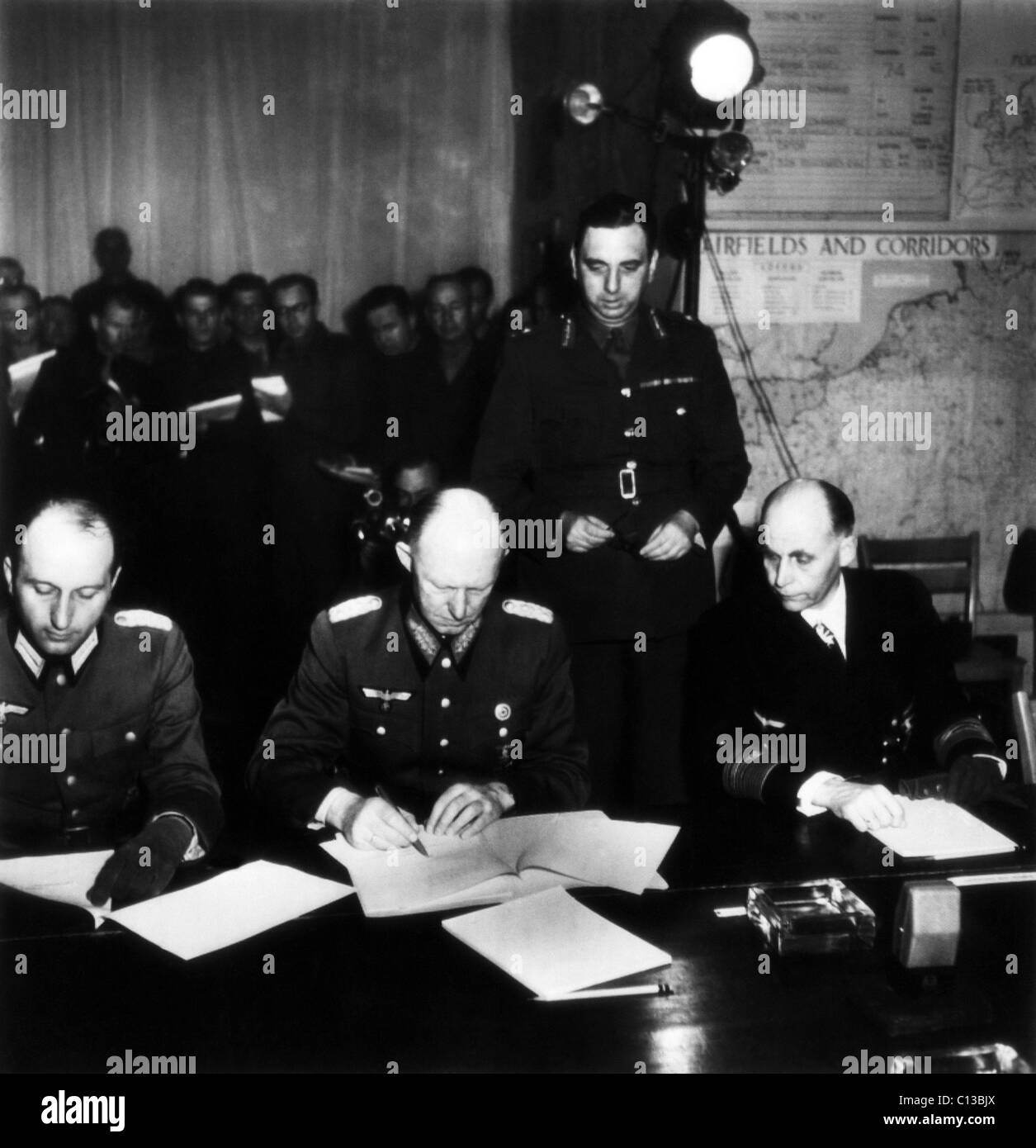 Alfred Jodl (center), Nazi Chief of Operations Staff, signs Germany's unconditional surrender at Allied headquarters, ending World War II in Europe. Jodl's personal aide, General Wilhelm Oxenius, sits at left, Admiral Hans Von Friedeburg, the Chief of the German Navy, sits at right, Reims, France, May 7, 1945. Stock Photo