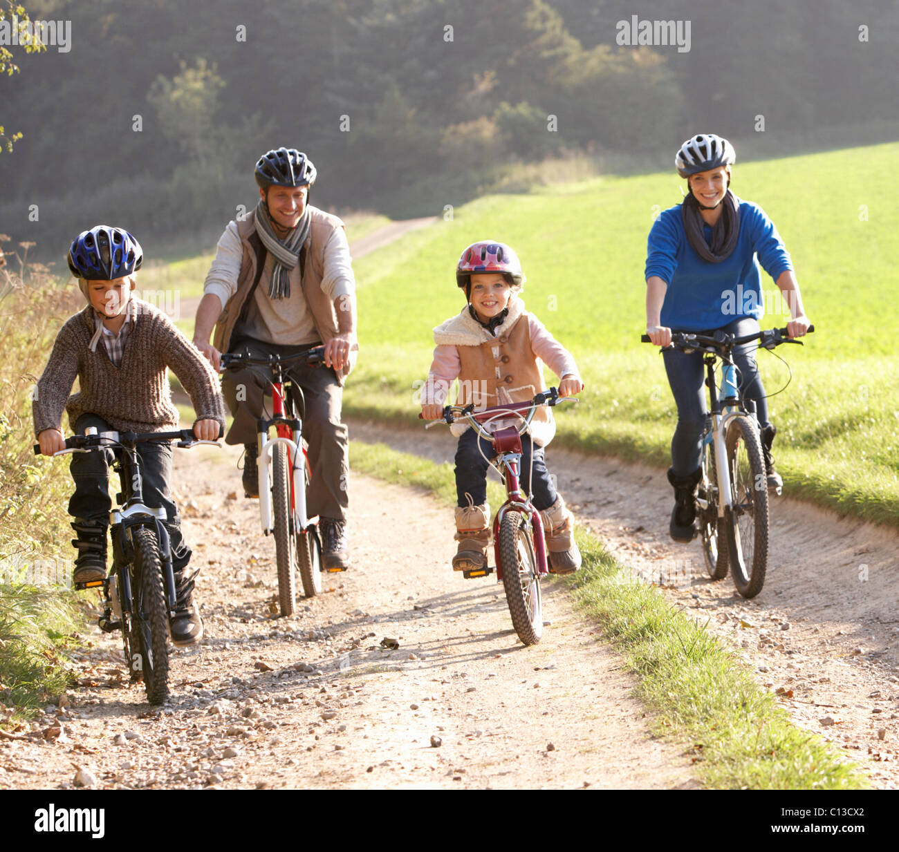 Young parents with children ride bikes in park Stock Photo