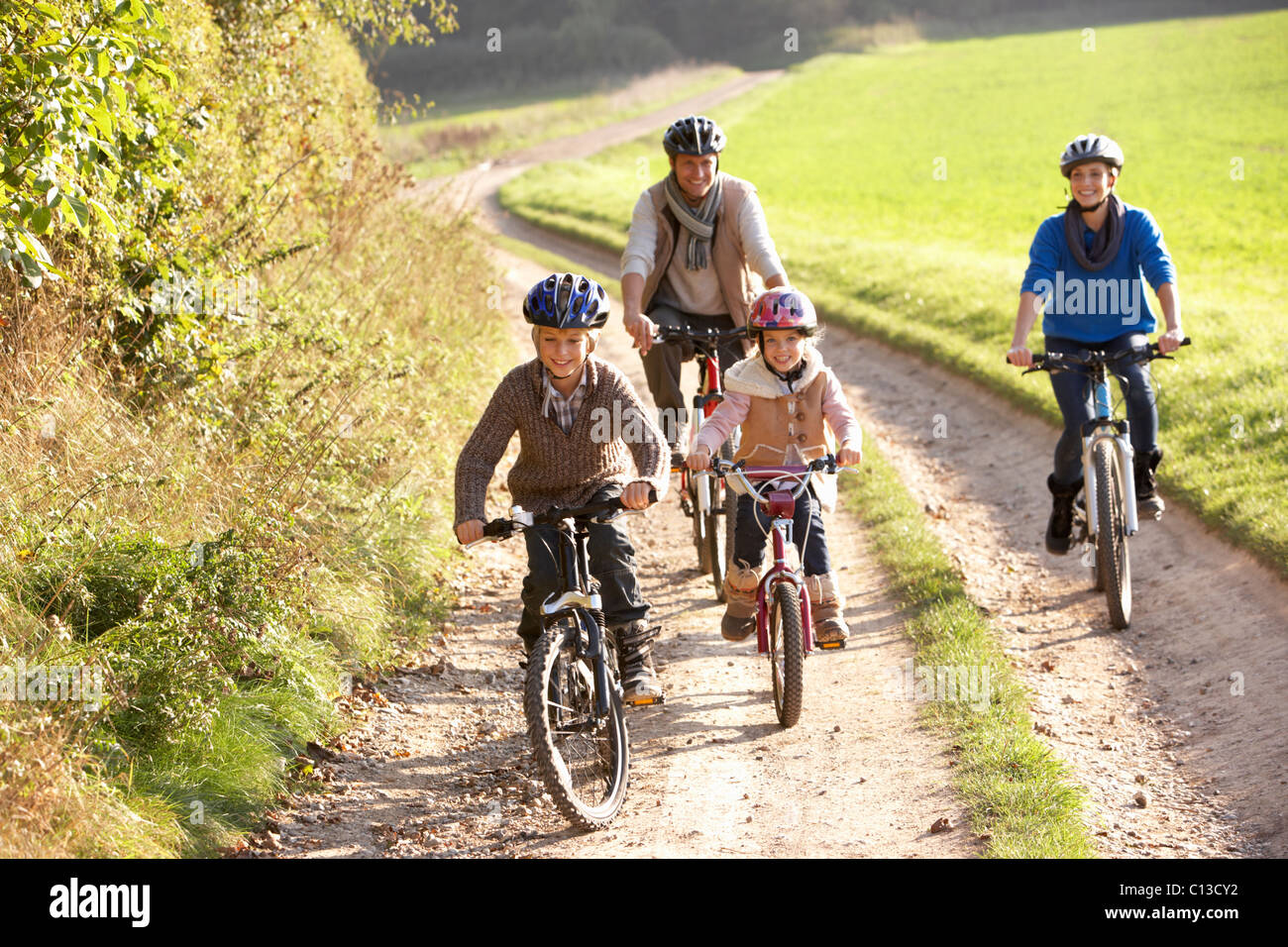 Young parents with children ride bikes in park Stock Photo