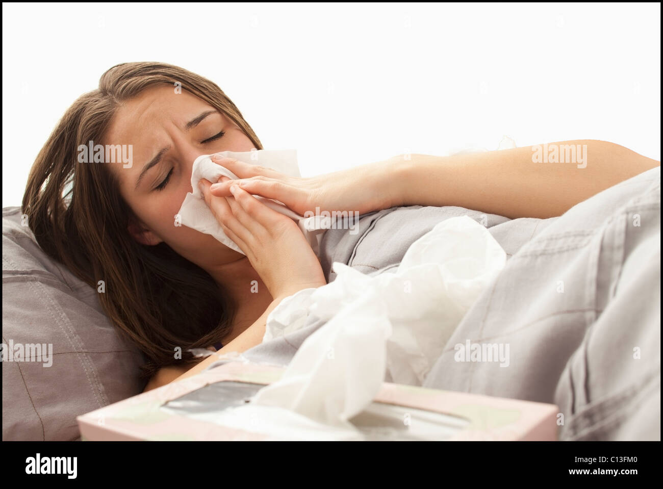 USA, Utah, Lehi, young woman lying in bed blowing nose Stock Photo