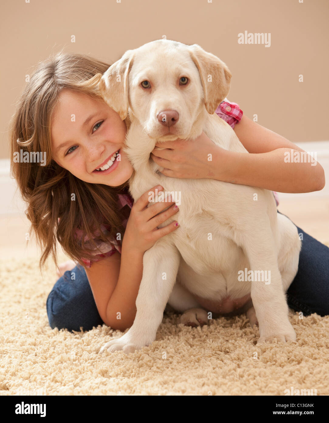 USA, Utah, Lehi, Portrait of girl (10-11) embracing Labrador on carpet Stock Photo