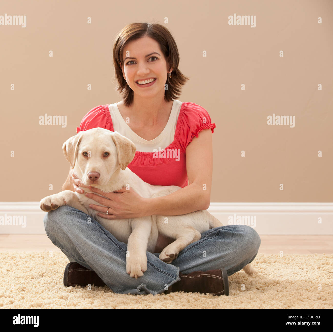 USA, Utah, Lehi, Portrait of woman embracing Labrador on carpet Stock Photo