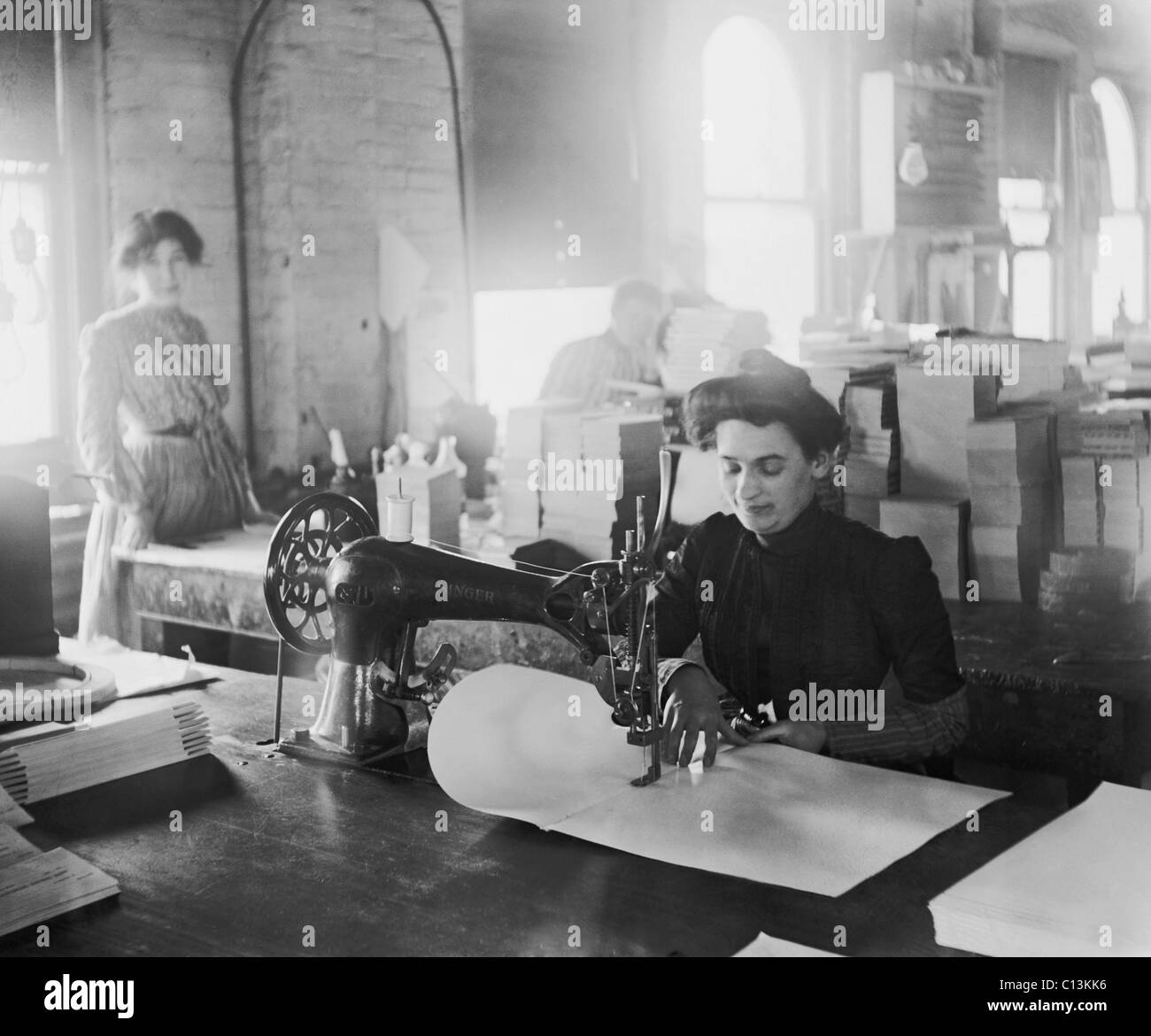 Middleaged women sewing on a belt driven Singer machine at the