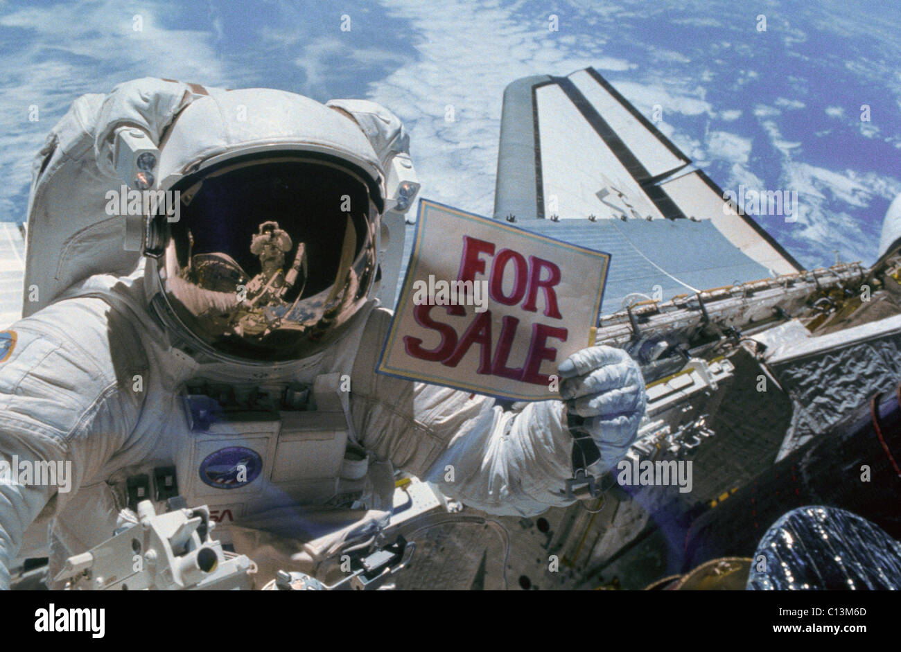 Astronaut Gardner holds a 'For Sale' sign after the orbital retrieval of two malfunctioning satellites the Western Union Telegraph Communication Satellite WESTAR VI and the PALAPA-B2 Satellite. The NASA Space shuttle program regularly contracted to launch commercial satellites. November 1984. Stock Photo