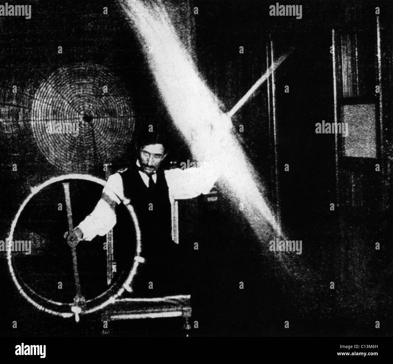 Nikola Tesla 1856-1943 conducted spectacular demonstrations of electricity. This image published in ELECTRICAL REVIEW in 1899 was accompanied by with this caption The operator's body in this experiment is charged to a high potential by means of a coil responsive to the waves transmitted to it from a distant oscillator. Stock Photo