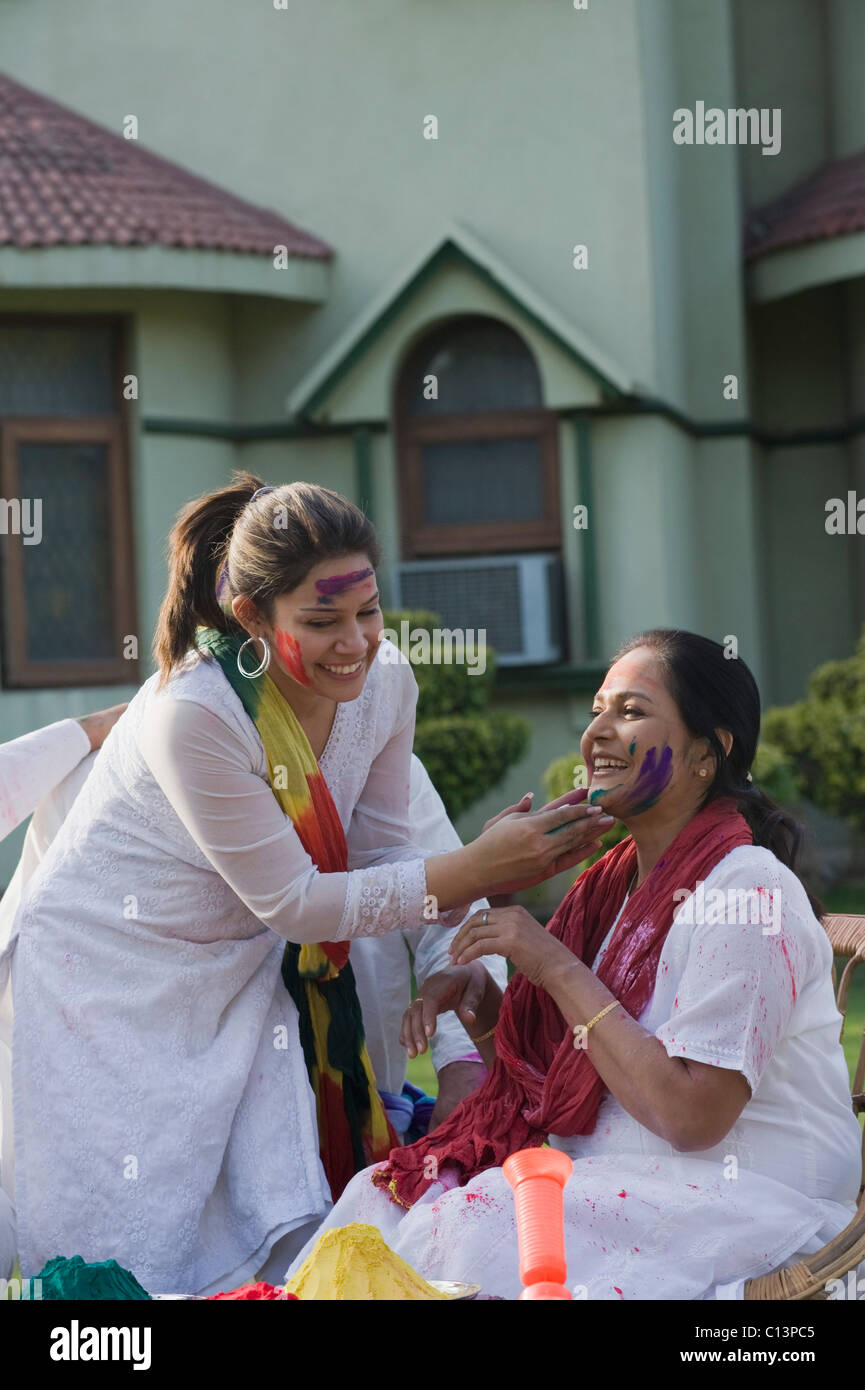 Woman applying Holi colors on her mother's face Stock Photo