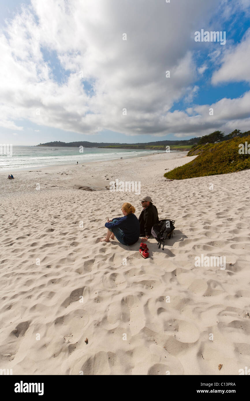 Couple sitting on white sand beach overlooking Pacific Ocean in Carmel, California, USA. Stock Photo