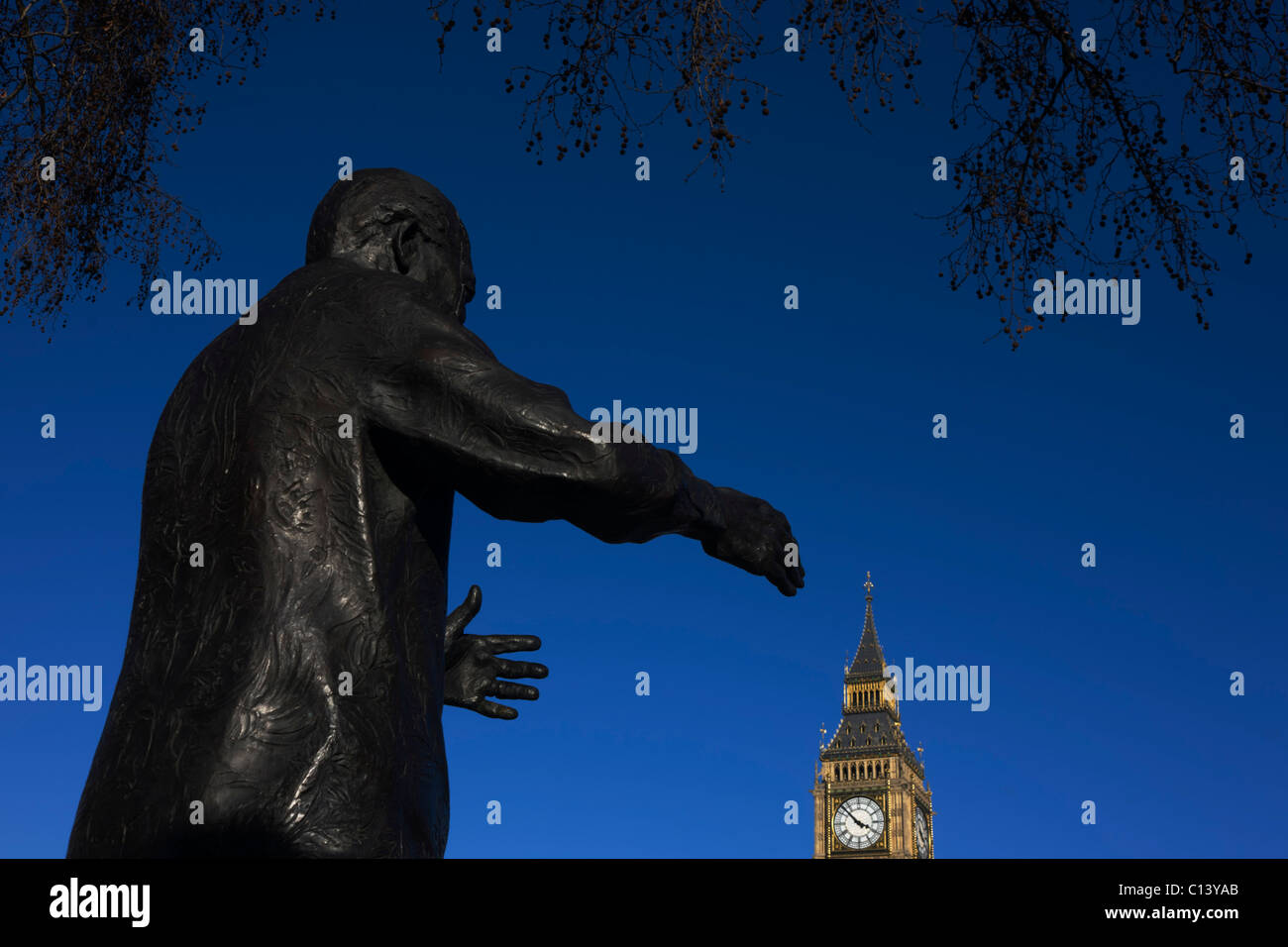 Reaching hands of ex-South African President Nelson Mandela's statue seemingly grasp Elizabeth Tower in Parliament Square. Stock Photo