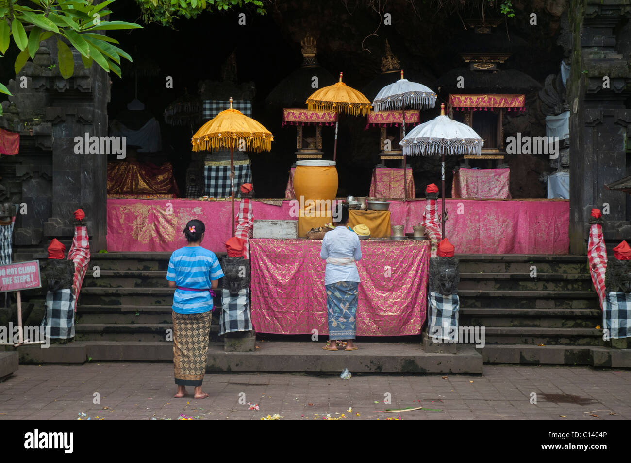 Two women make offerings at the altar in the 1000 year old bat cave temple called Pura Goa Lawah in Klungkung, Eastern Bali near Padang Bai Stock Photo