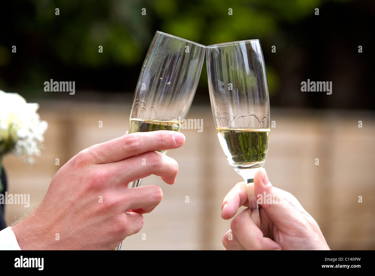 Two hands joining glasses of champagne in celebration Stock Photo