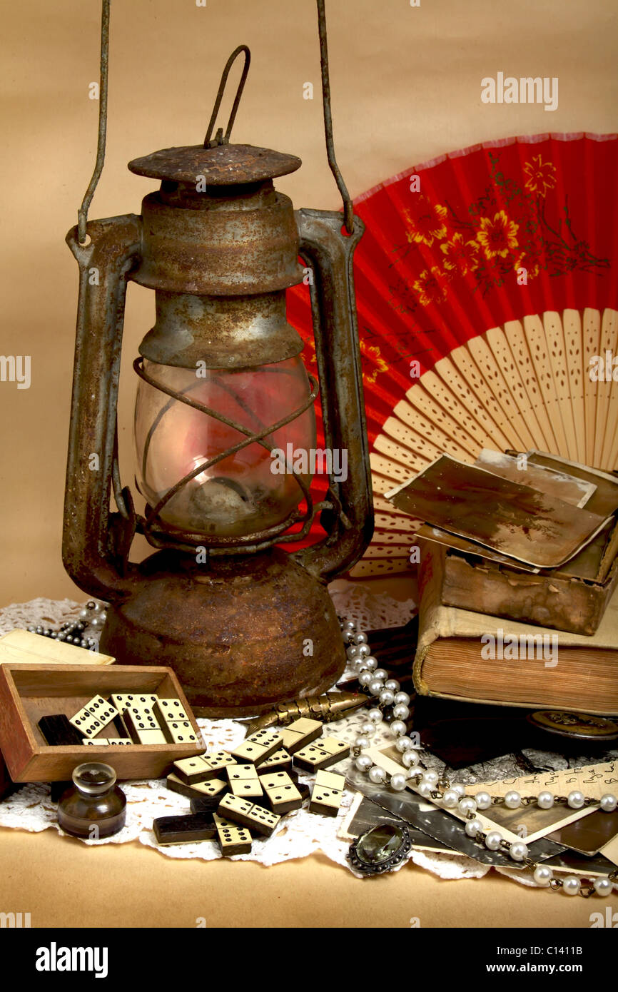 Still life oil lamp, old photos, antique domino and jewelry Stock