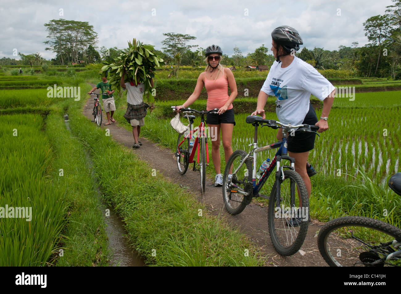 Mountain bike touring through villages and rice paddies in Bali Indonesia Stock Photo