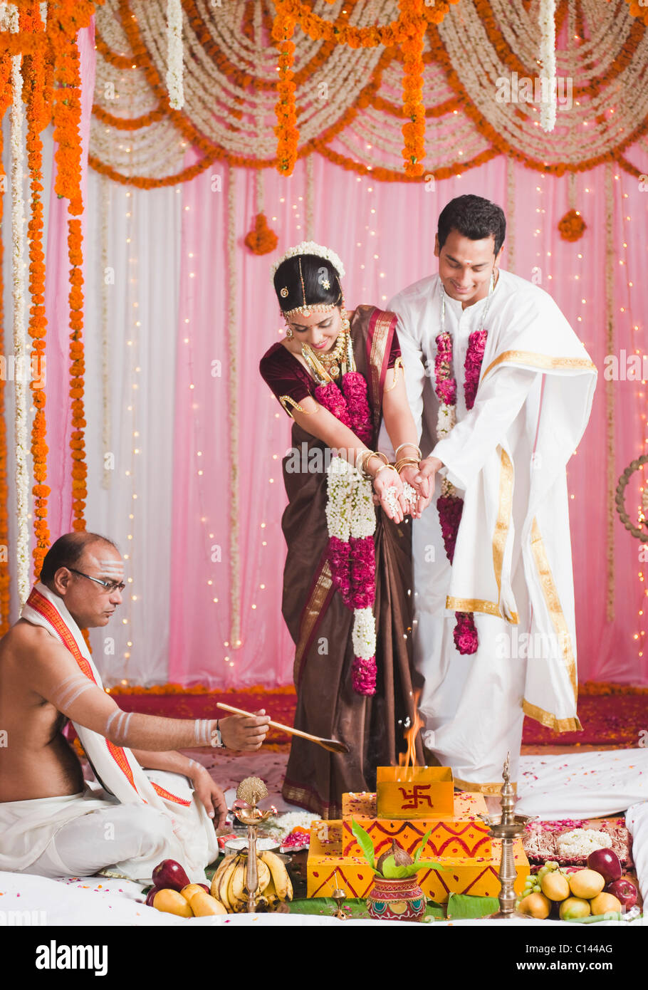 Bride and bridegroom performing a religious ceremony during south ...