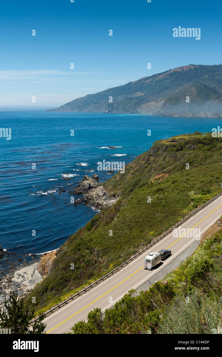 Vehicle towing travel trailer on California Highway 1 winds along the Big Sur coastline with view of the Pacific Ocean. Stock Photo