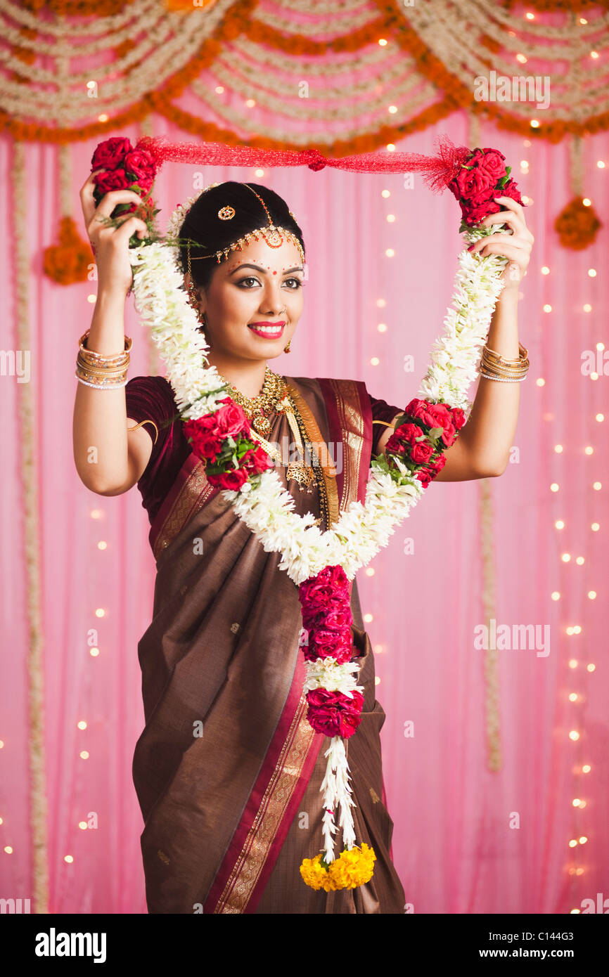 Bride in traditional South Indian dress holding a garland and smiling Stock Photo