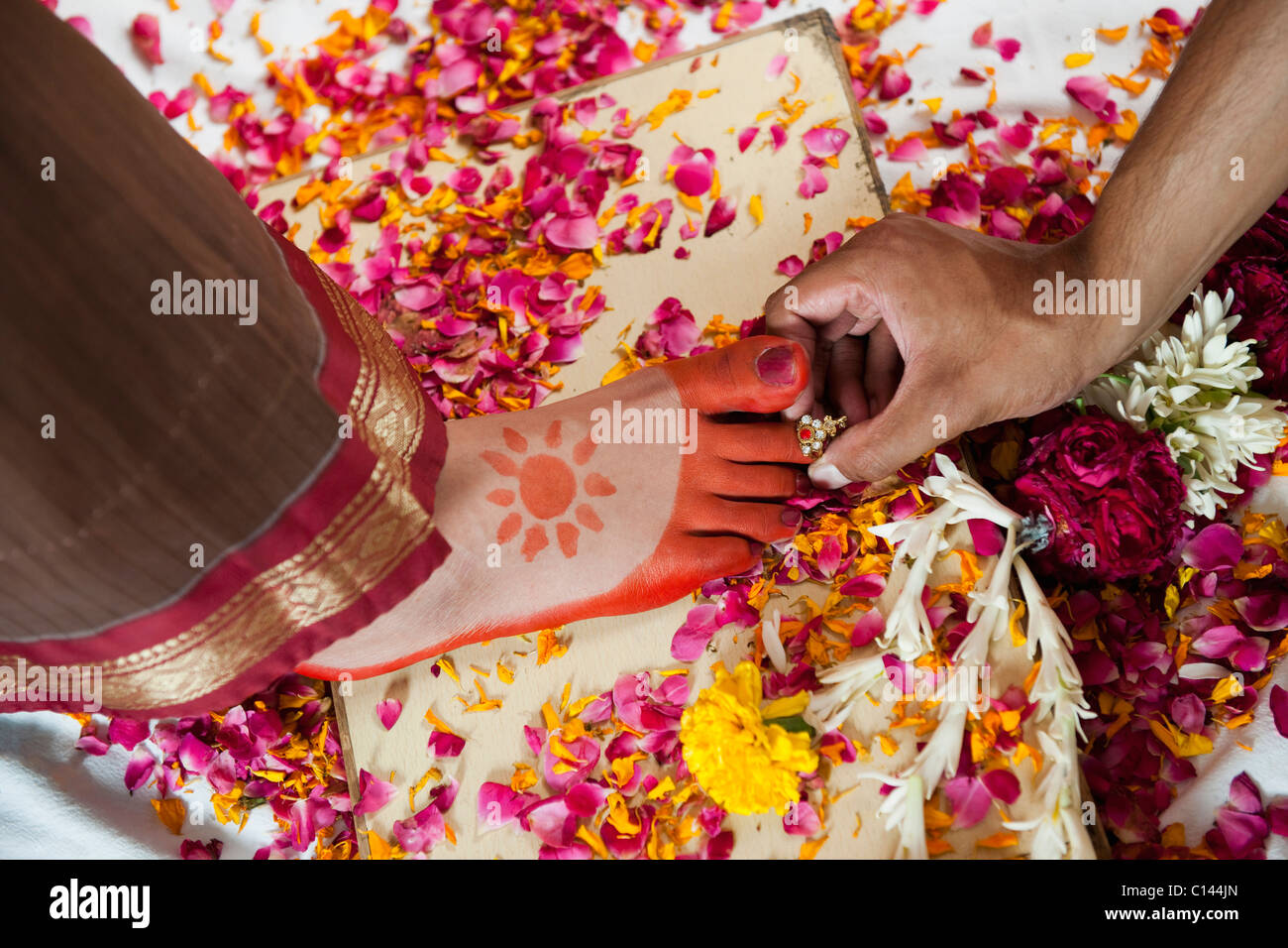 Bridegroom putting a toe ring onto the bride's toe during South Indian wedding ceremony Stock Photo