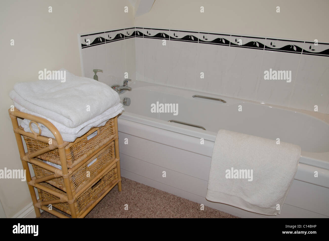 White bathroom with white towels on a wicker stand Stock Photo