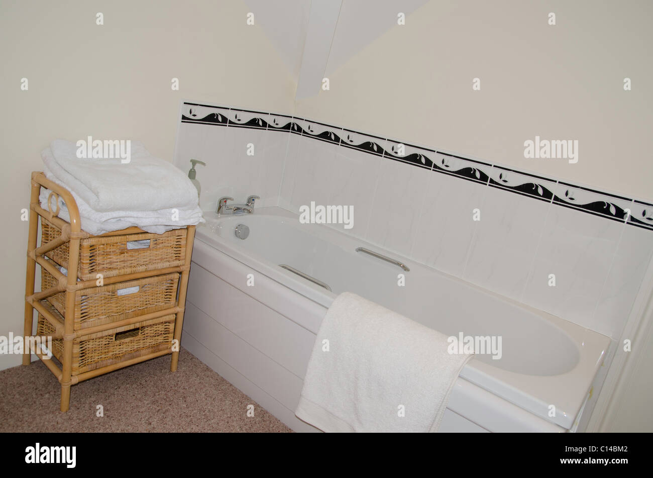 White bathroom with white towels on a wicker stand Stock Photo