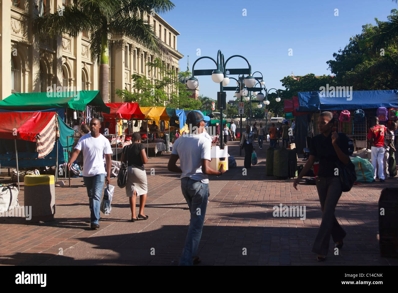 Hawkers setting up colourful street-side stalls along a busy city thoroughfare in central Durban, South Africa. Stock Photo