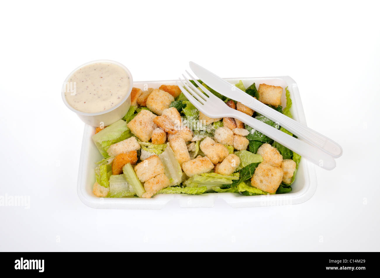 Ready to eat Caesar Salad with cheese, croutons and dressing with utensils on white background, cutout. Stock Photo