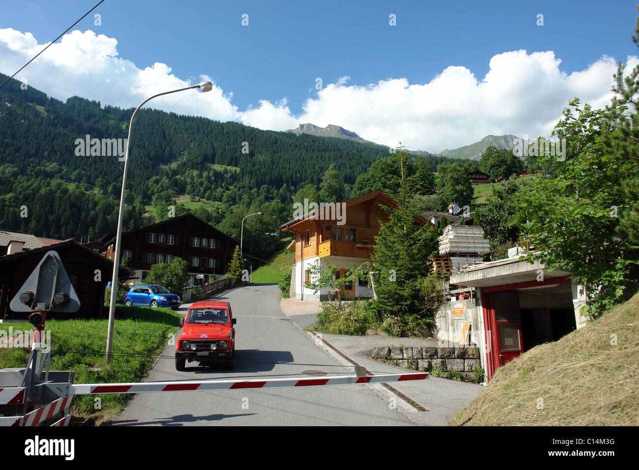 Vehicle at traffic intersection in Switzerland, as seen from train passing through. Beautiful background with green mountains. Stock Photo