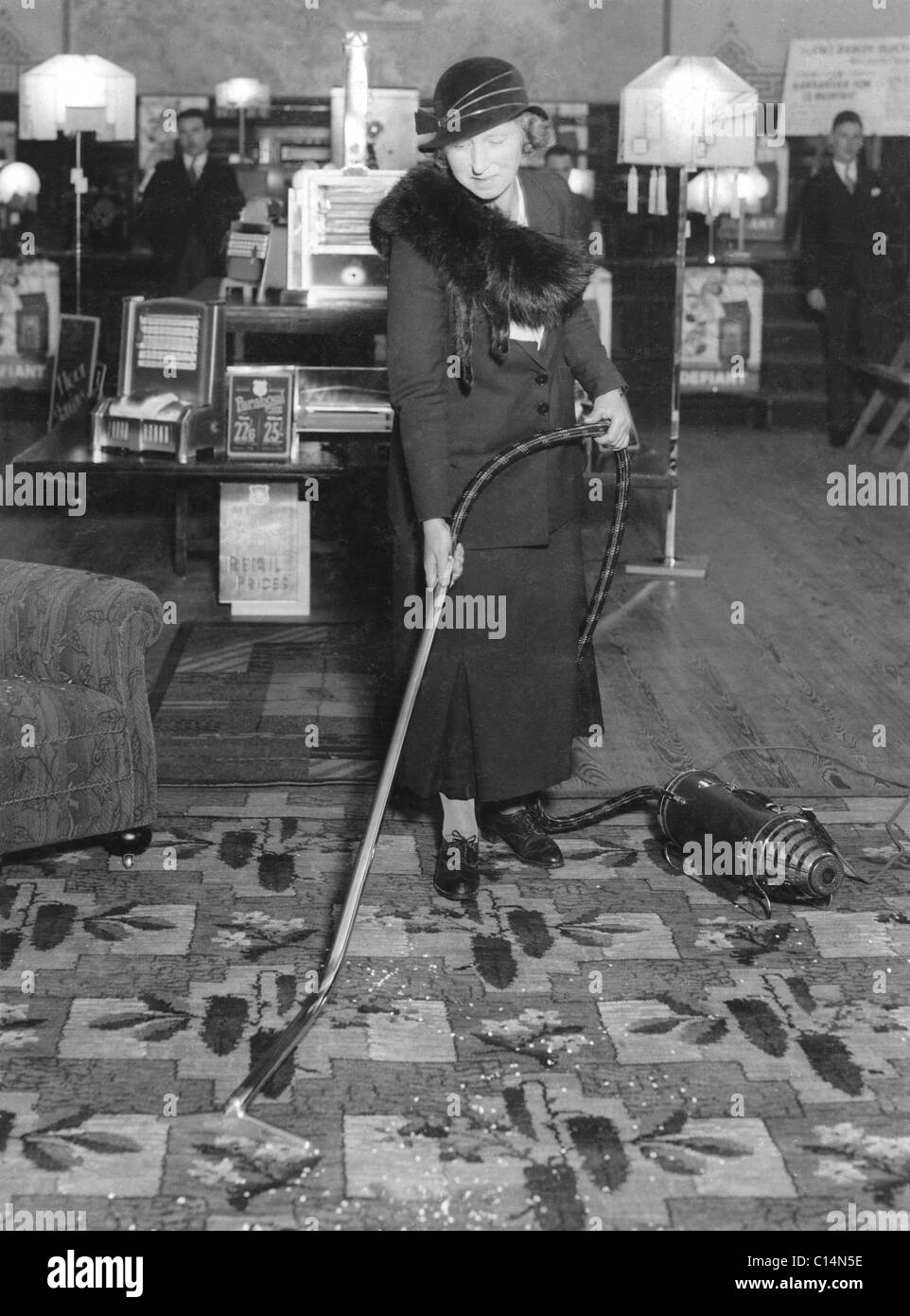 Woman demonstrator staff or customer demonstrating using a vacuum cleaner in U.K. furniture shop showroom UK circa. 1930-1933 Stock Photo
