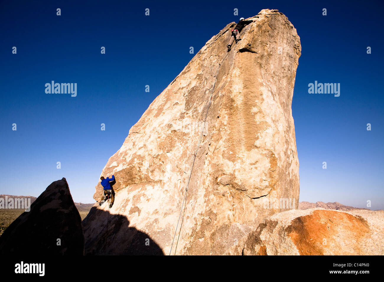 Two male climbers work their way up Headstone Rock in Joshua Tree