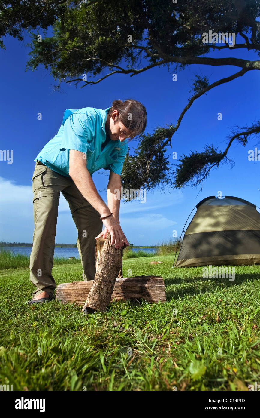 Young man stack wood at a campsite on the banks of Shelby Lakes in Gulf Shores Alabama. Stock Photo