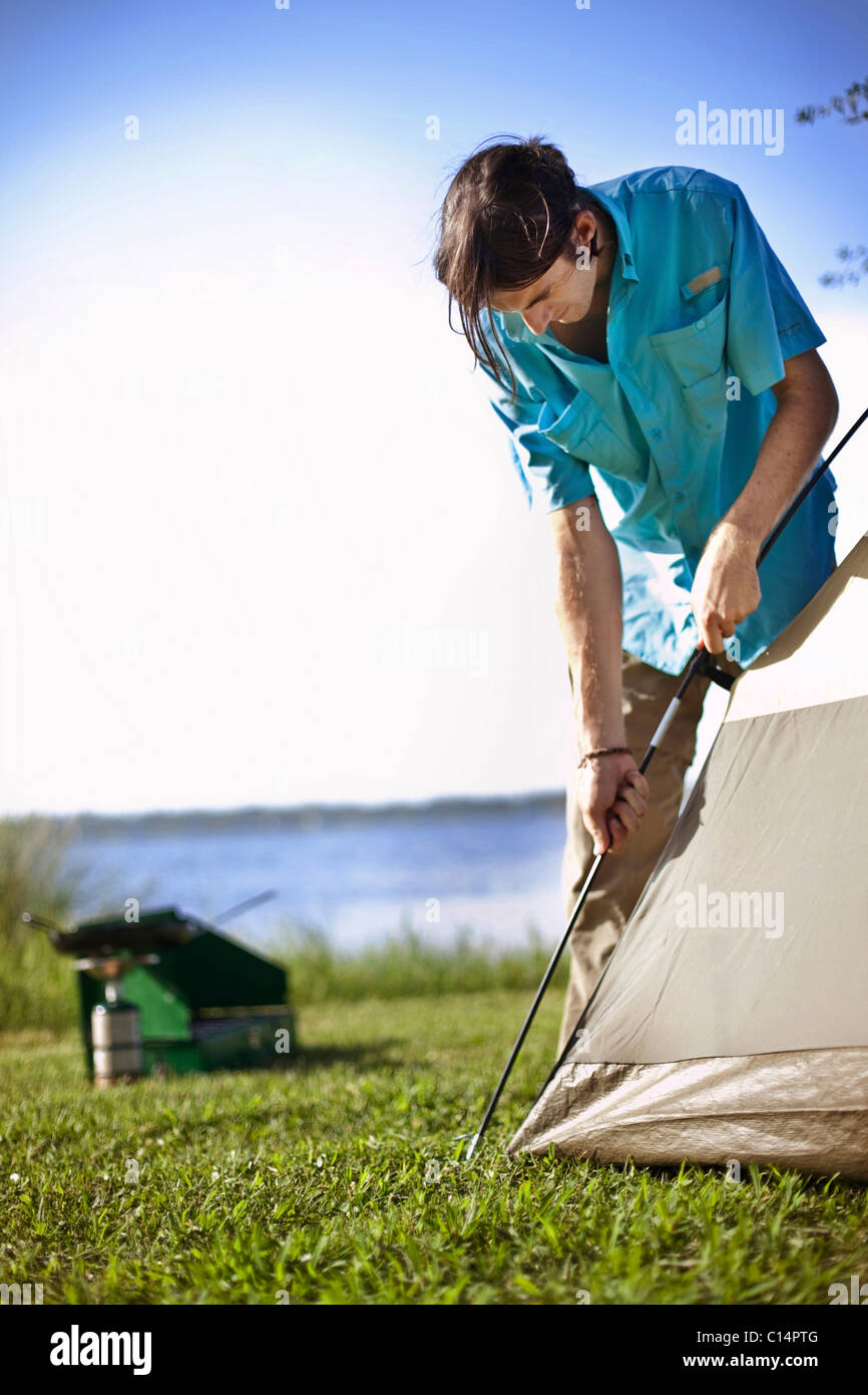 Young man assembles a tent on the banks of Shelby Lakes in Gulf Shores Alabama. Stock Photo