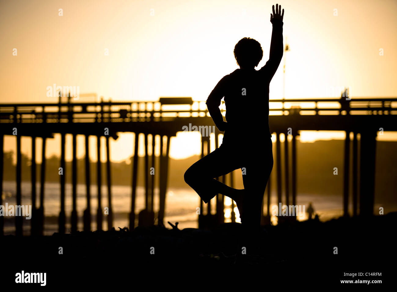A silhouetted woman does yoga on the beach in Ventura, California. Stock Photo