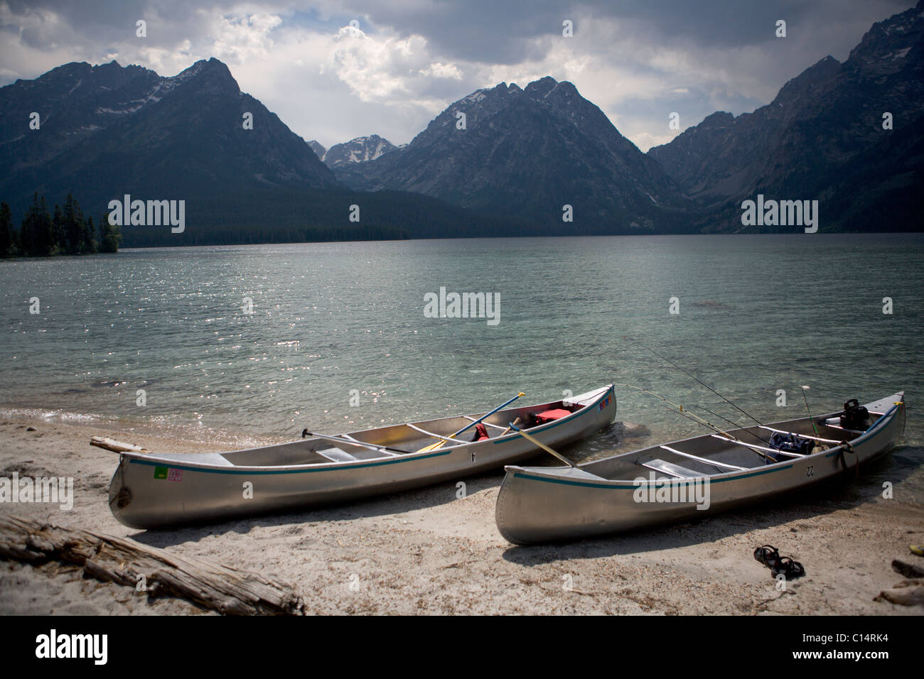 Two canoes are beached on the shore of Lake Leigh with the Grand Tetons in the distance. Stock Photo