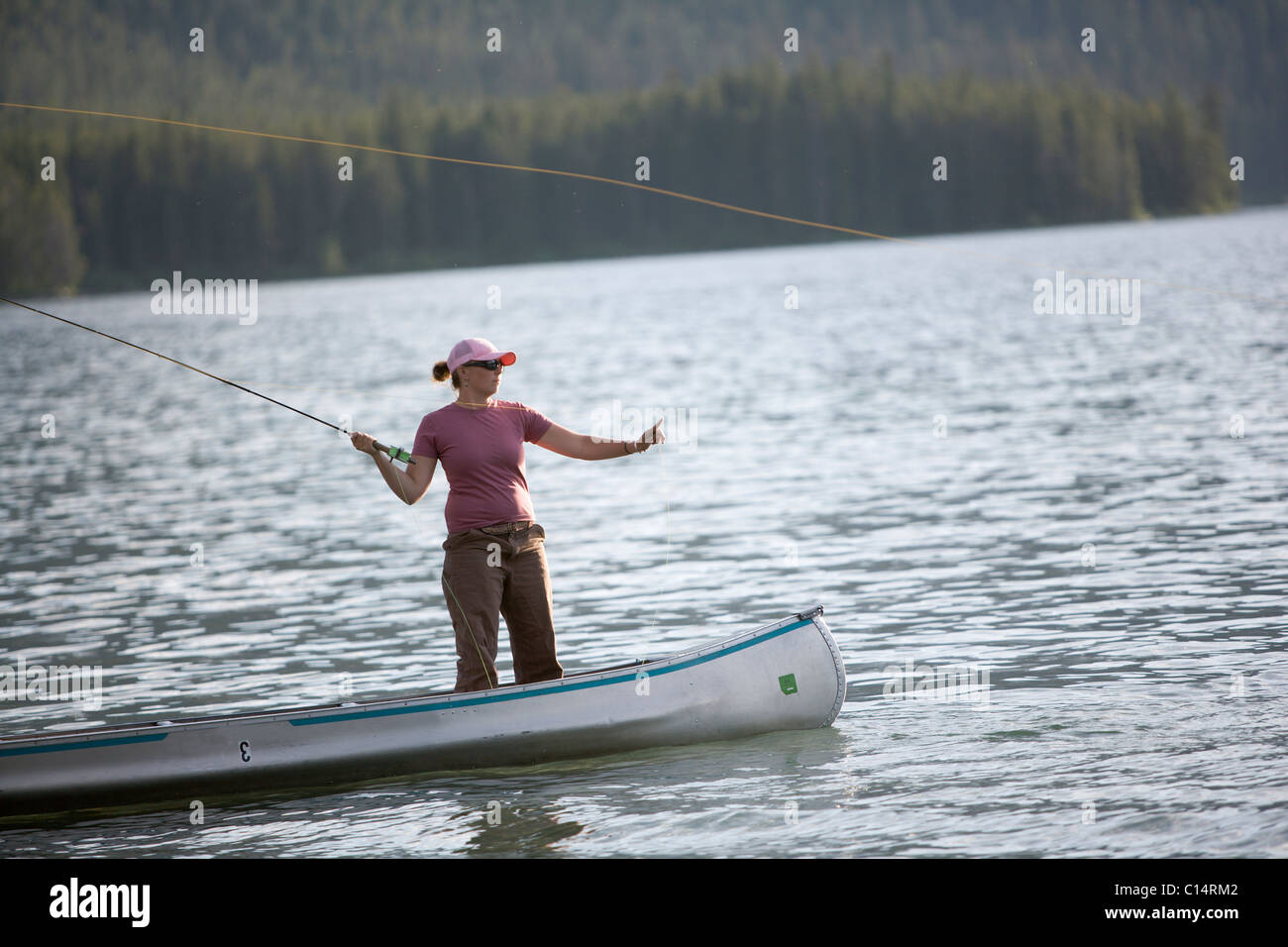 A woman casts her flyline while on a canoe. Stock Photo