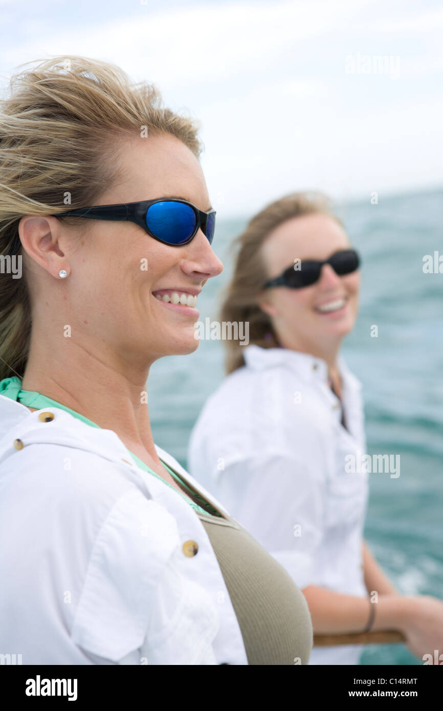 Two women with sunglasses smile with the ocean in the background. Stock Photo
