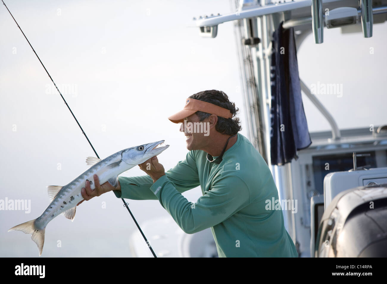 A fisherman smiles at the barracuda he has just caught. Stock Photo