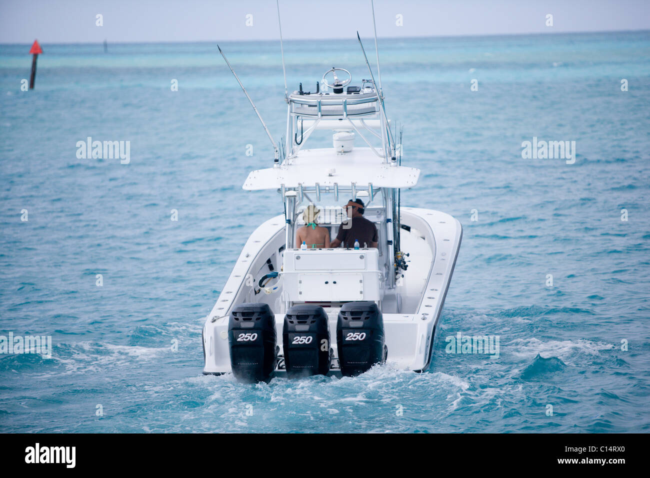 A man and woman on a fishing boat head out to blue-green water for a day of deep sea fishing. Stock Photo