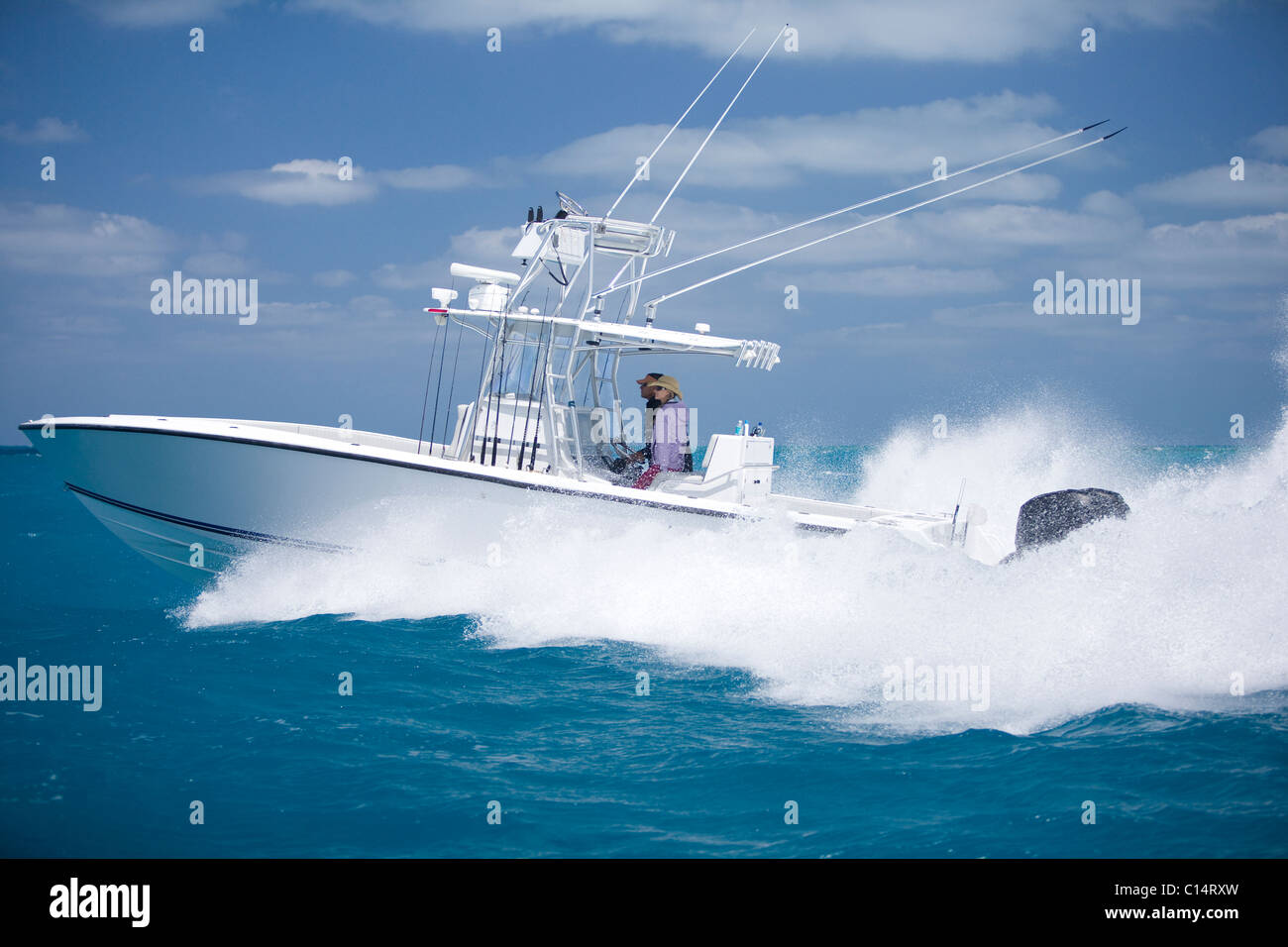 A fishing boat speeds through the blue surf spraying white water. Stock Photo