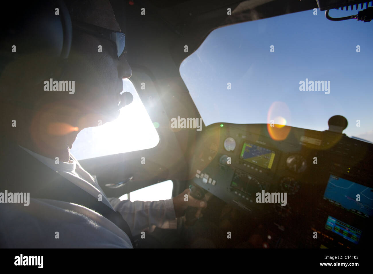 a sunflared view of a pilot flying his plane looking out at the blue sky. Stock Photo