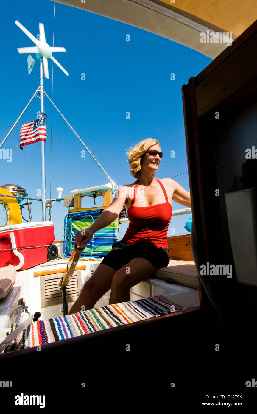 A woman in a red bathing suit gets some sun onboard a sail boat in the Bahamas. Stock Photo