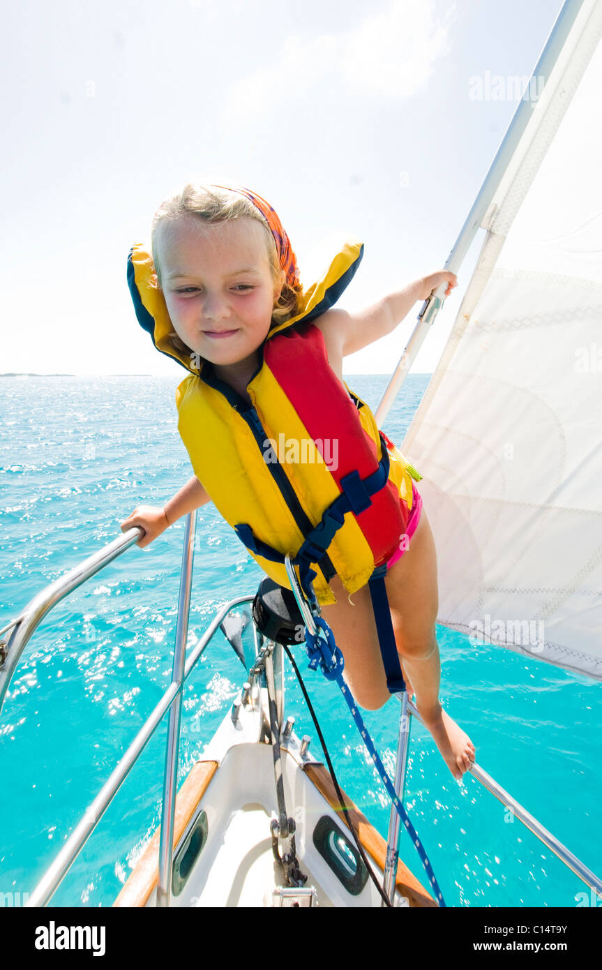 A young girl balances on the railing of a sail boat in the Bahamas. Stock Photo