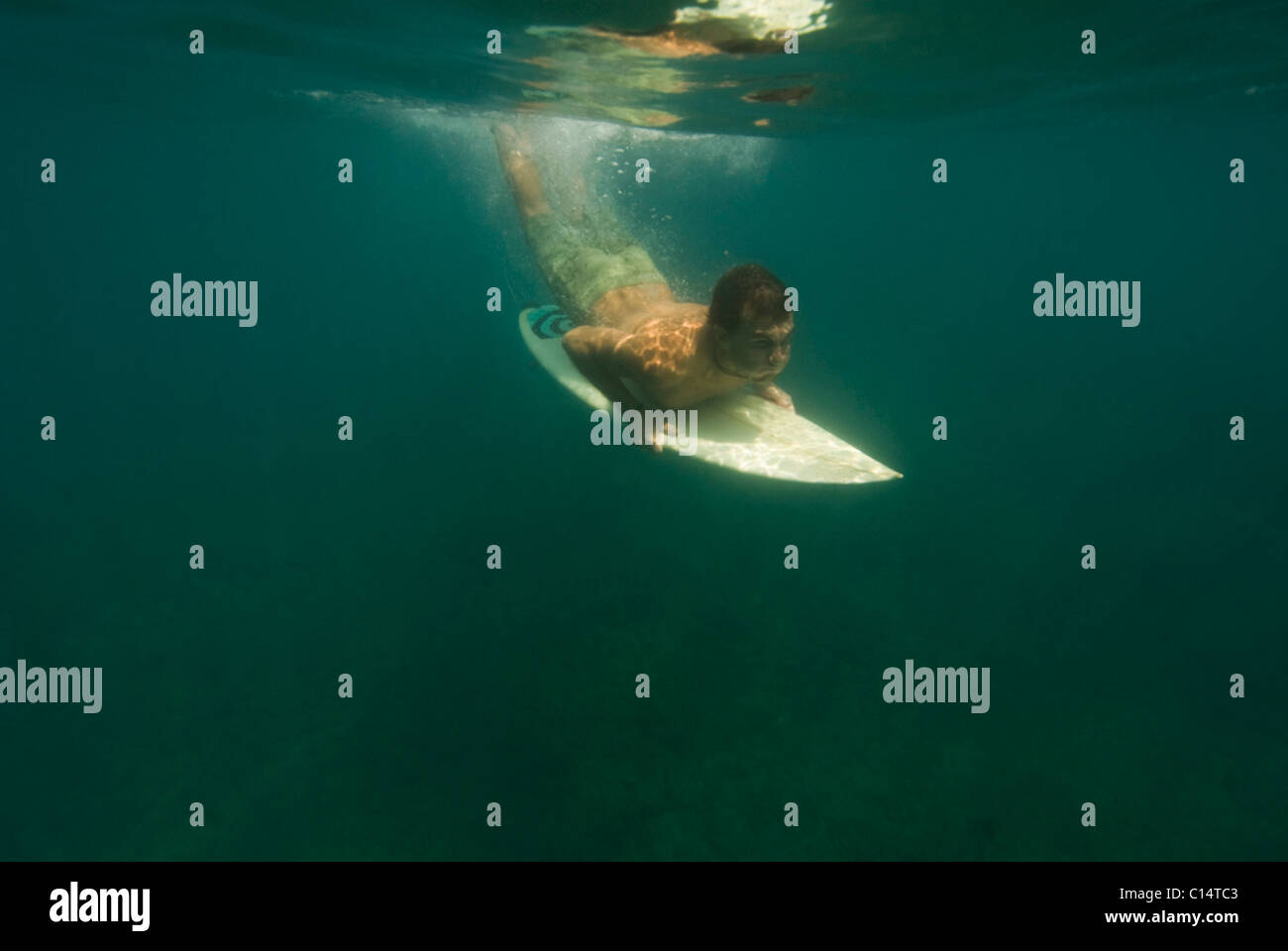 A young man diving underwater with his surfboard in Costa Rica Stock Photo