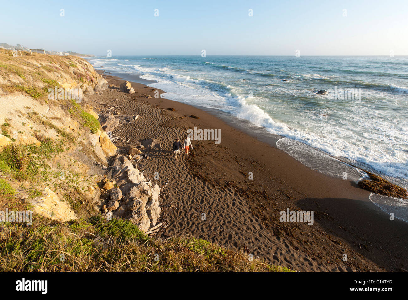 Couple walking on sandy beach overlooking Pacific Ocean at Moonstone Beach in Cambria, California. Stock Photo