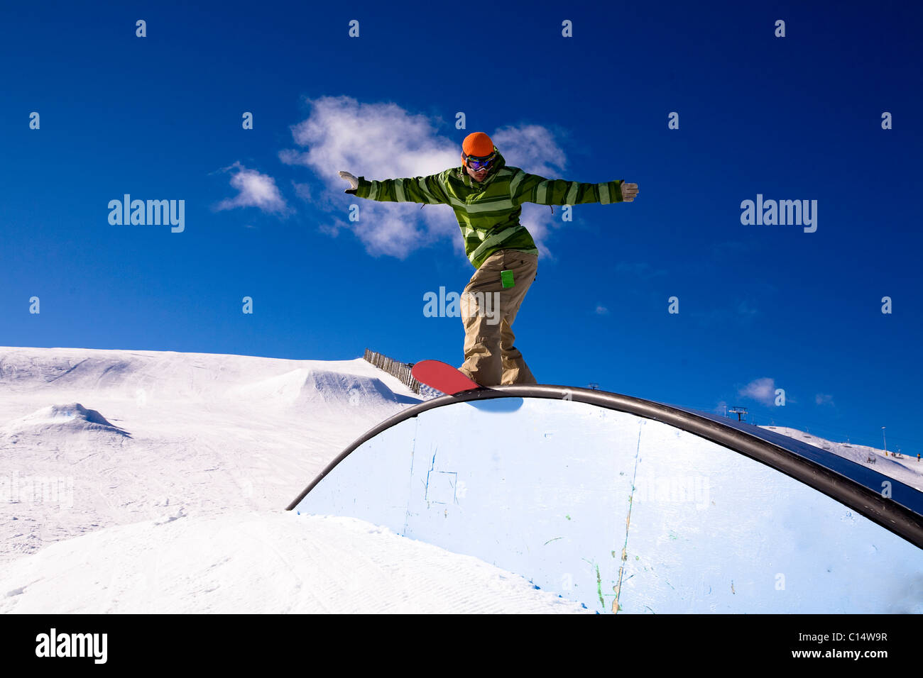 A male snowboarder rides a rail while snowboarding at Snow Park in Wanaka, New Zealand. Stock Photo